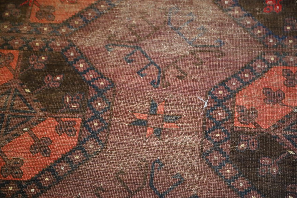 An Afghan aubergine and red ground carpet, with field of octagons and geometric motifs, 350 x 274cm